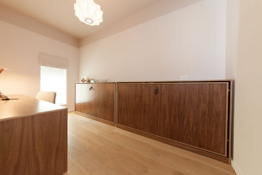 Two twin walnut Murphy beds with leather straps in closed position in white room 