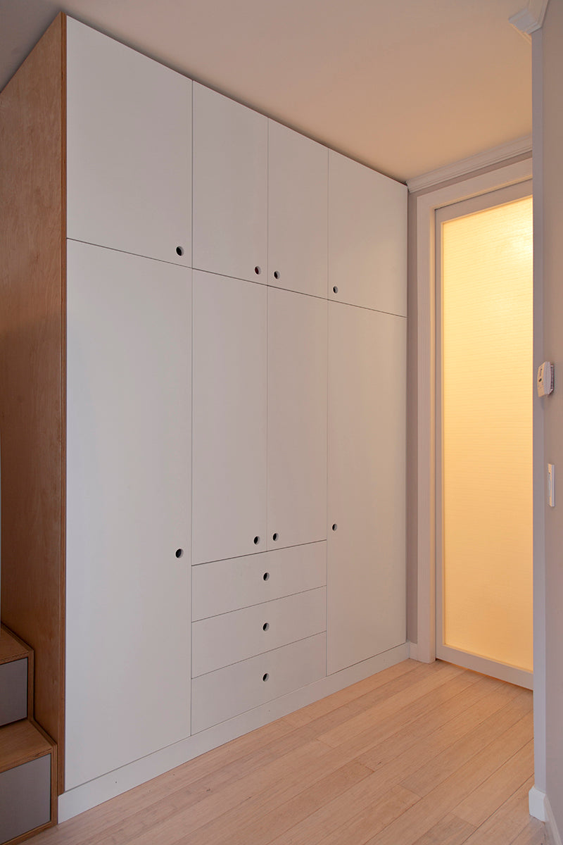 White wardrobe, wooden floor, open door.