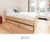 Custom platform bed in natural birch with built-in underbed storage drawers, designed for a compact bedroom with modern furnishings.