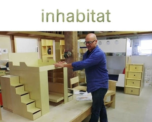 Man demonstrating a multifunctional wooden furniture setup in a workshop environment.