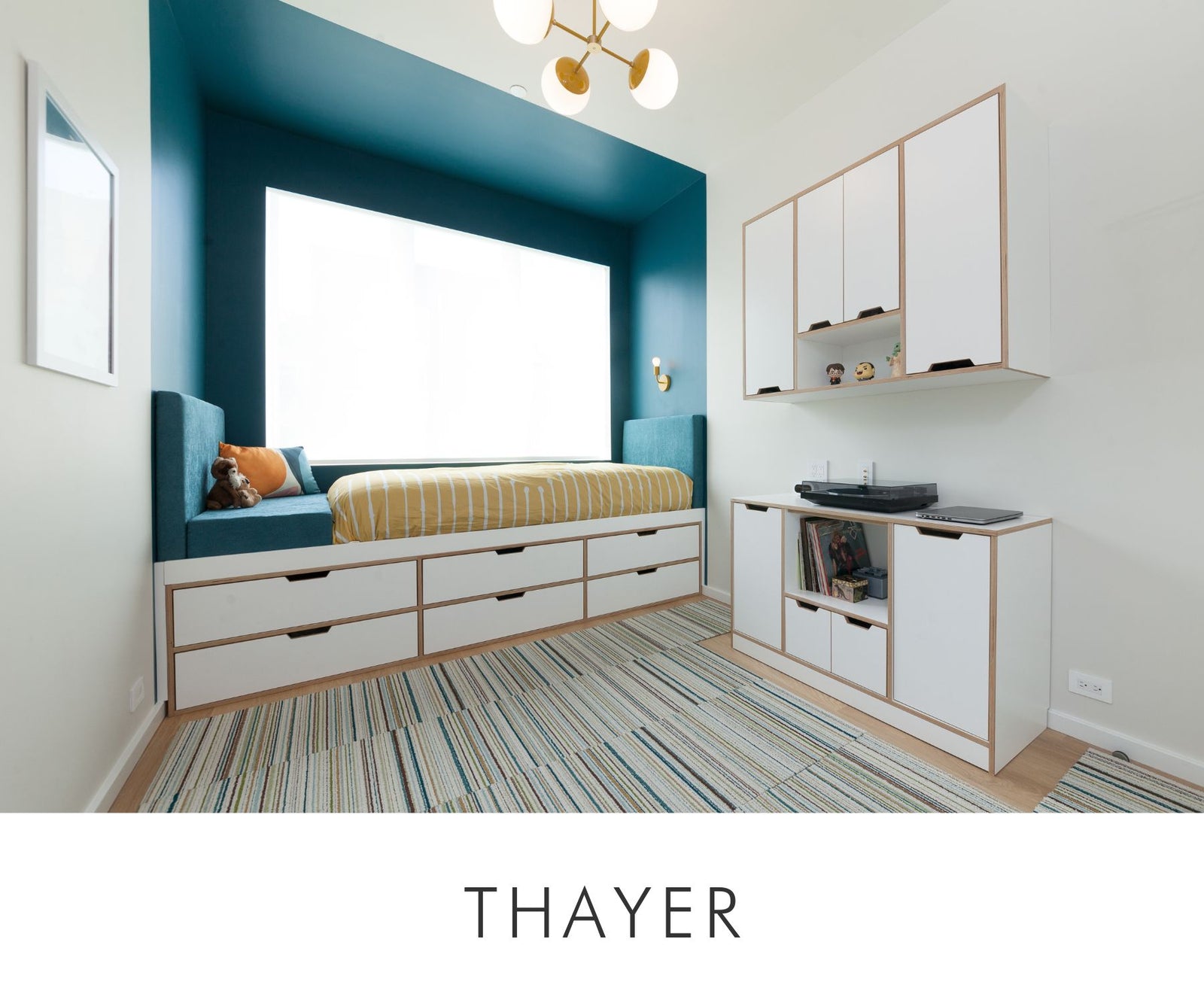 Custom upholstered bed with underbed storage drawers, paired with a white lower cabinet housing a record player and a matching floating wall cabinet above.