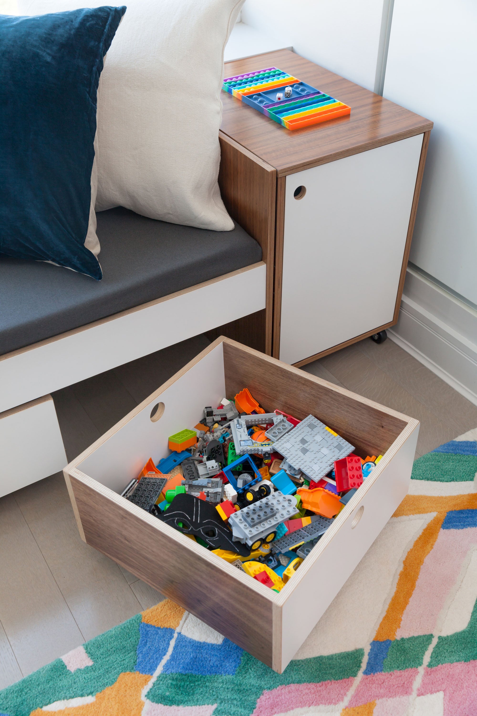 close up of toy cart with legos inside. walnut finish with white accents