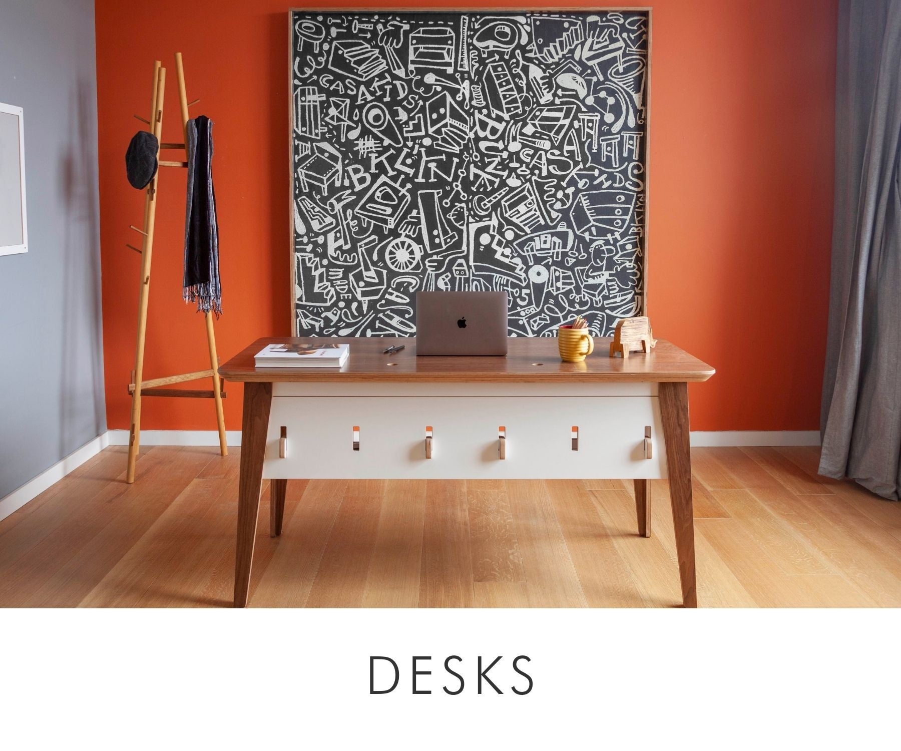 Custom walnut and white desk in a modern home office setting, featuring a bold black-and-white chalkboard artwork, warm-toned walls, and a sleek wooden coat rack.