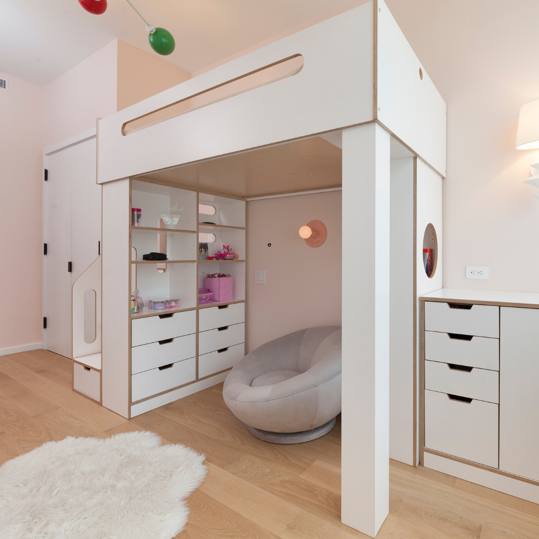 White loft bed with open storage shelves and drawers underneath, complemented by a cozy gray chair and a soft rug in a pastel-colored room.