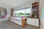 Daybed with built-in storage drawers, flanked by bookshelves and a window seat, featuring a white oak finish with white painted accents in a bright children's room.

