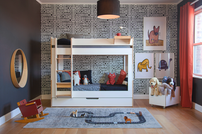 Birch and white Cabin Bunk Bed with rectangular cutouts, attached ladder, trundle bed and grey bedding against a black and white patterned wall paper kid's room.