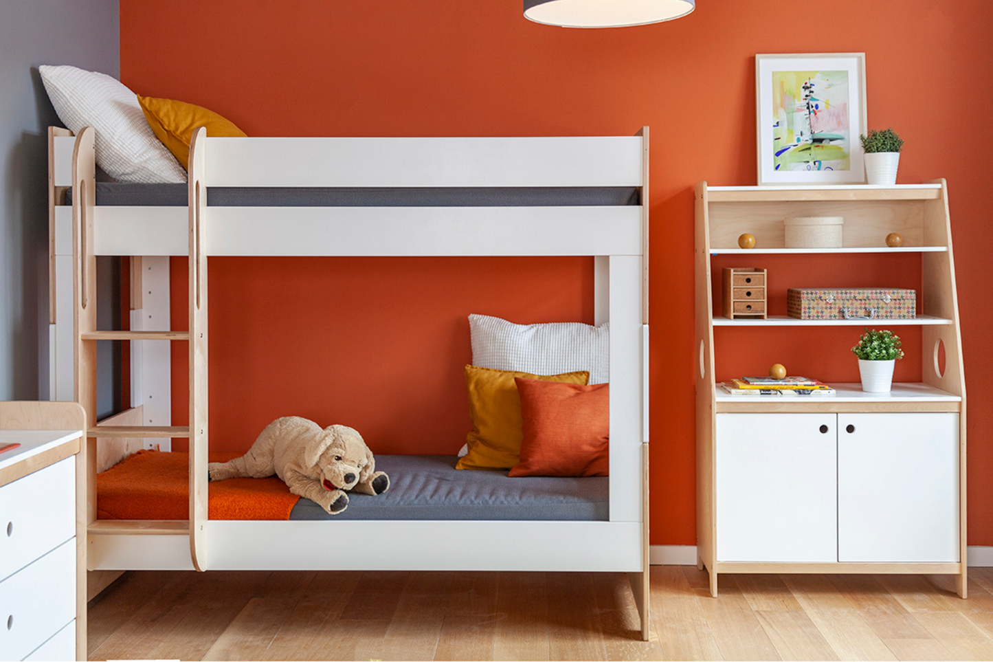 Birch and white Cabin Bunk Bed with rectangular cutouts, attached ladder, and grey bedding against a red wall with matching armoire in a kid's room