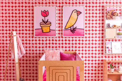 Katie Merz Framed Artwork of a flower pot, baby chick, on pink and white spot wallpaper in kid's room with a light wood crib, pink pillows, and floating light wood shelf.